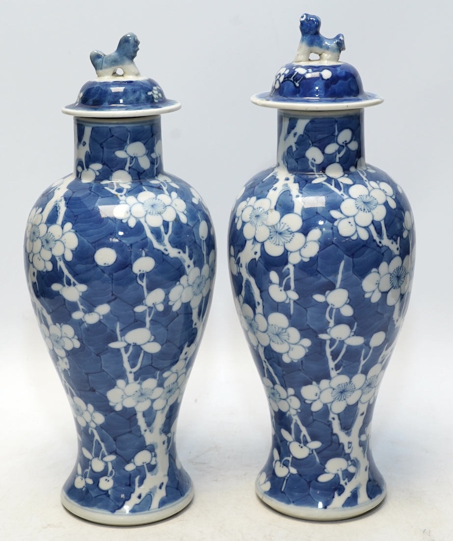 A pair of Chinese blue and white prunus baluster vases and covers, 31cm high. Condition - one vase good, the other pieces poor